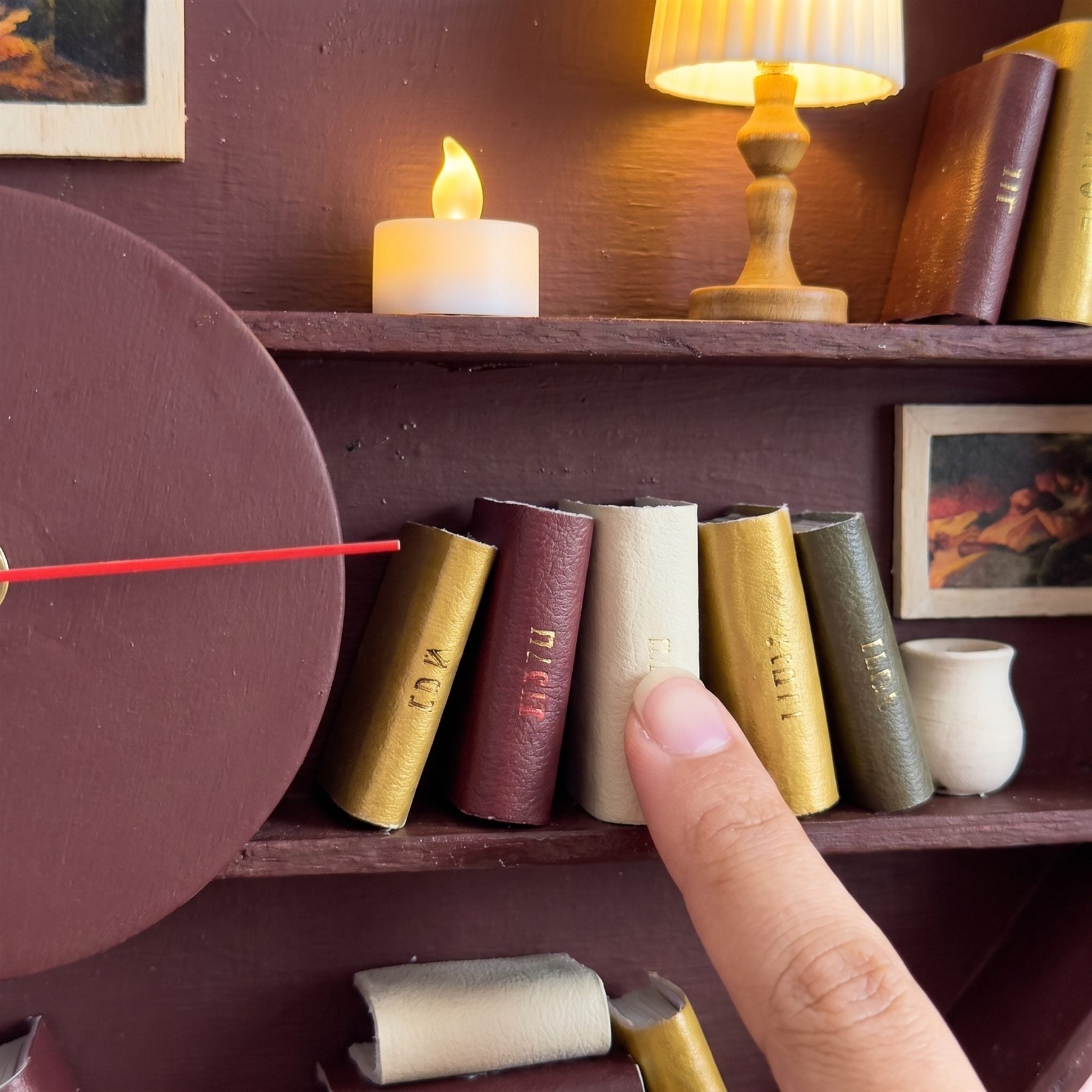Close-up of miniature leather books and a lit candle inside the clock